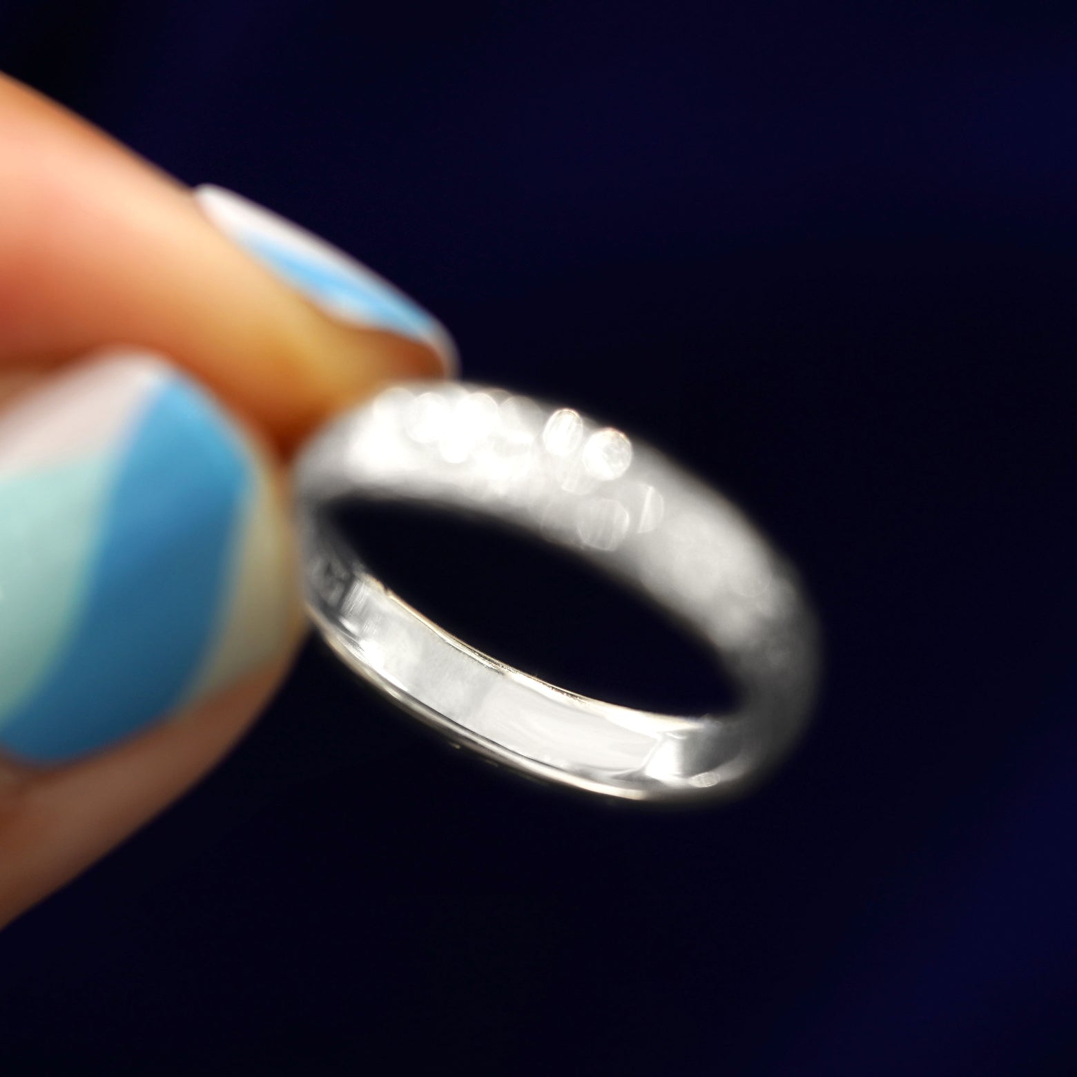 A model holding a Silver Raw Band tilted to show the inside of the ring