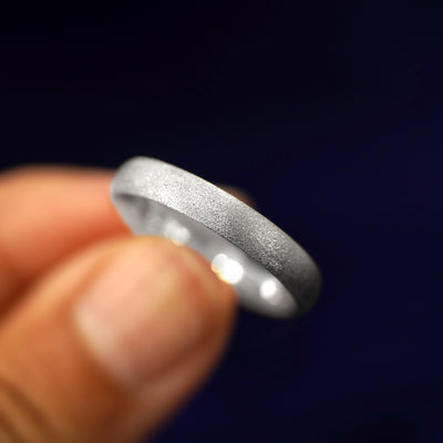 A model holding a Silver Curvy Stardust Band tilted to show the details of the star dust finish