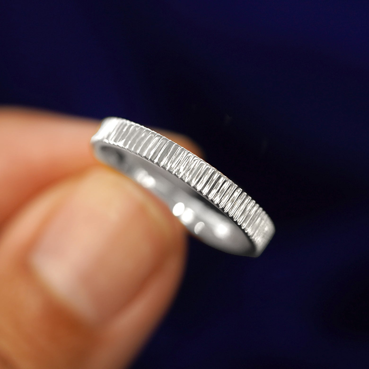 A model holding a Silver Edge Band tilted to show the details of the star dust finish