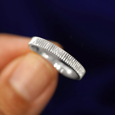 A model holding a Silver Edge Band tilted to show the details of the star dust finish