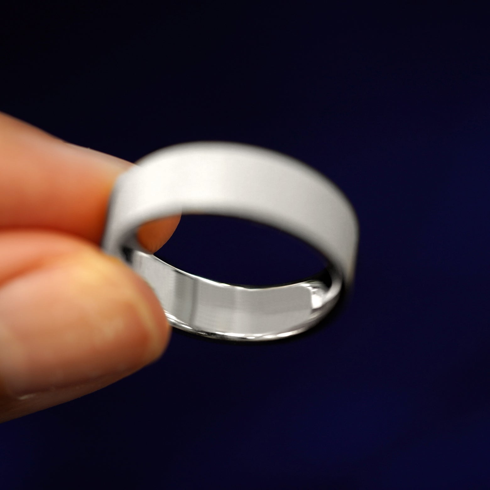 A model holding a Silver Industrial Stardust Band tilted to show the inside of the ring