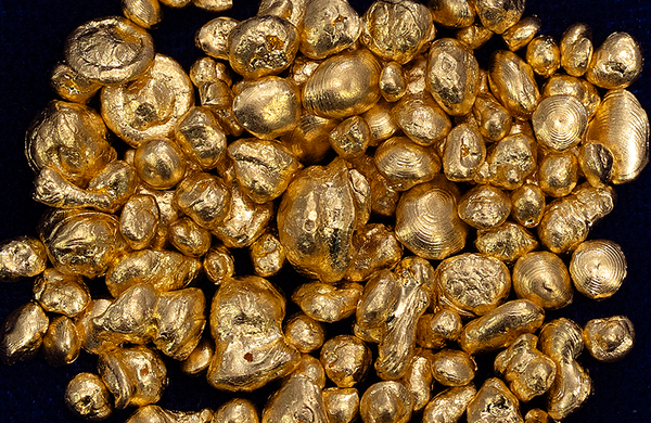 A pile of solid gold nuggets on a dark blue cloth