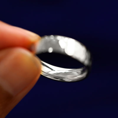 A model holding a Silver Industrial Hammered Band tilted to show the inside of the band