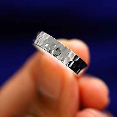 A model holding a 925 silver Industrial Hammered Band tilted to show the details of the hammered finish