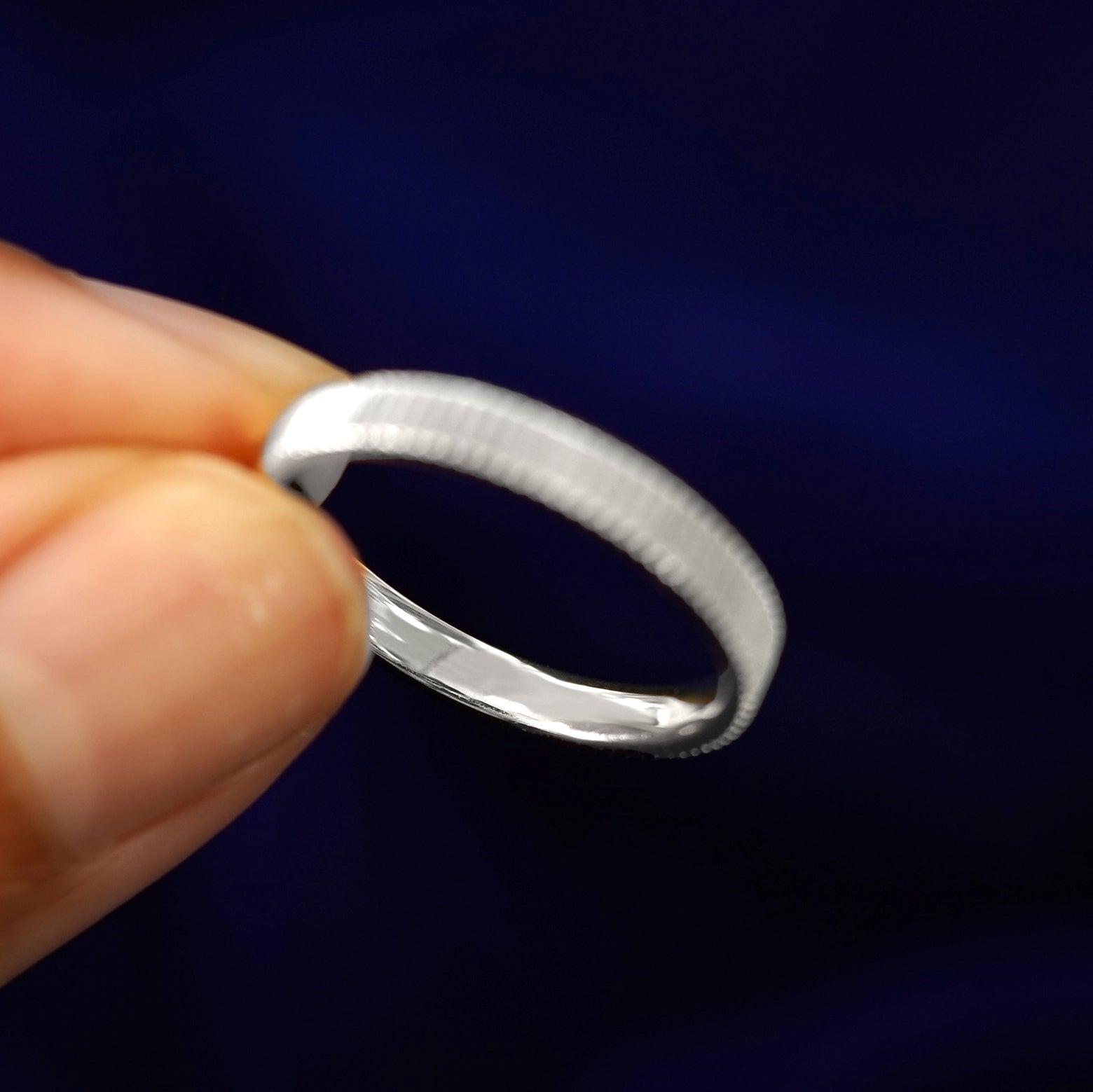 A model holding a Silver Edge Band tilted to show the inside of the ring