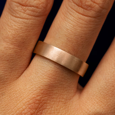 Close up view of a model's fingers wearing a 14k rose gold Industrial Matte Band