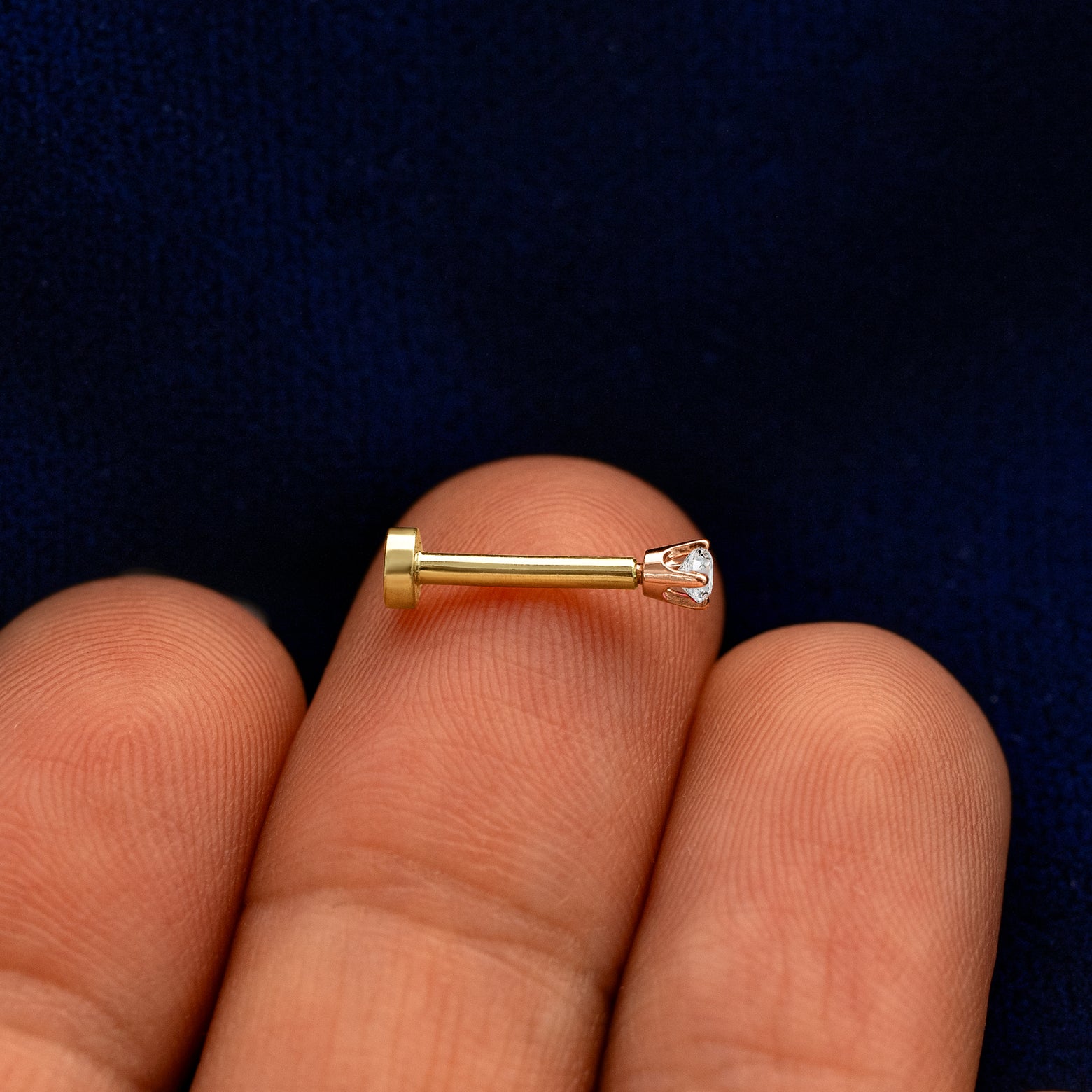 Side view of a 14k rose gold 2mm Diamond Flatback Piercing on a model's fingertips
