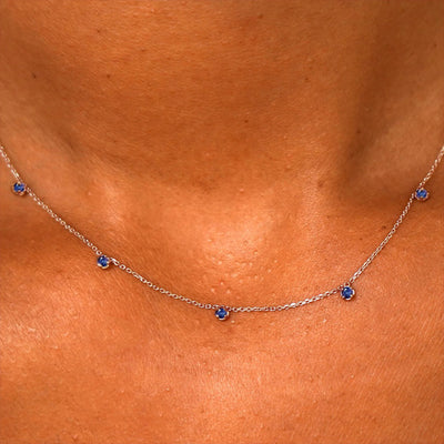 Close up view of a model's neck wearing a solid 14k rose gold 5 Gemstone Cable Necklace in sapphire
