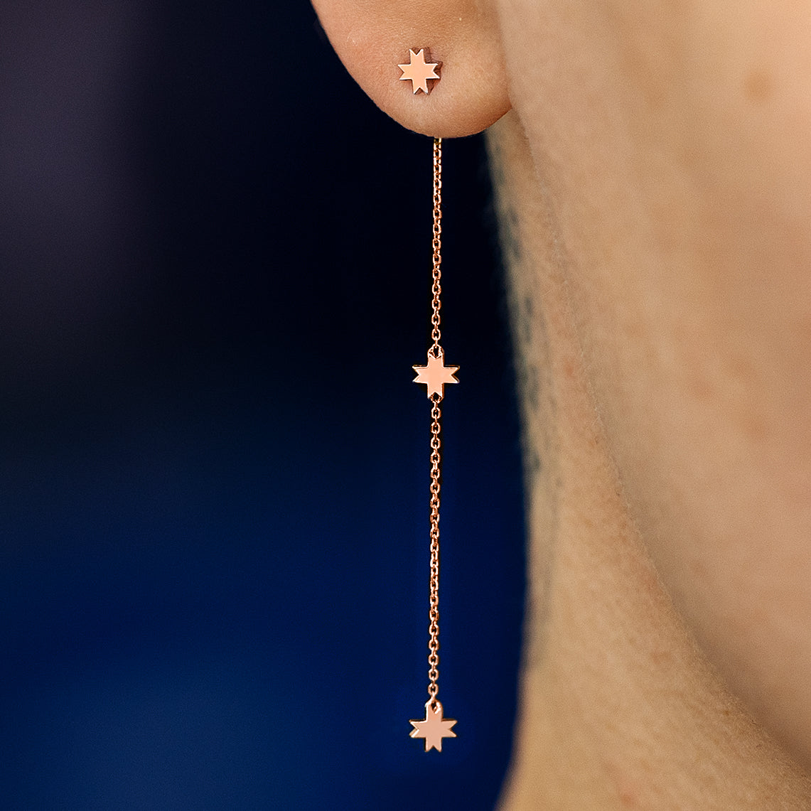 Close up view of a model wearing a 14k rose gold 8 pointed star extender with an 8 pointed star stud earring