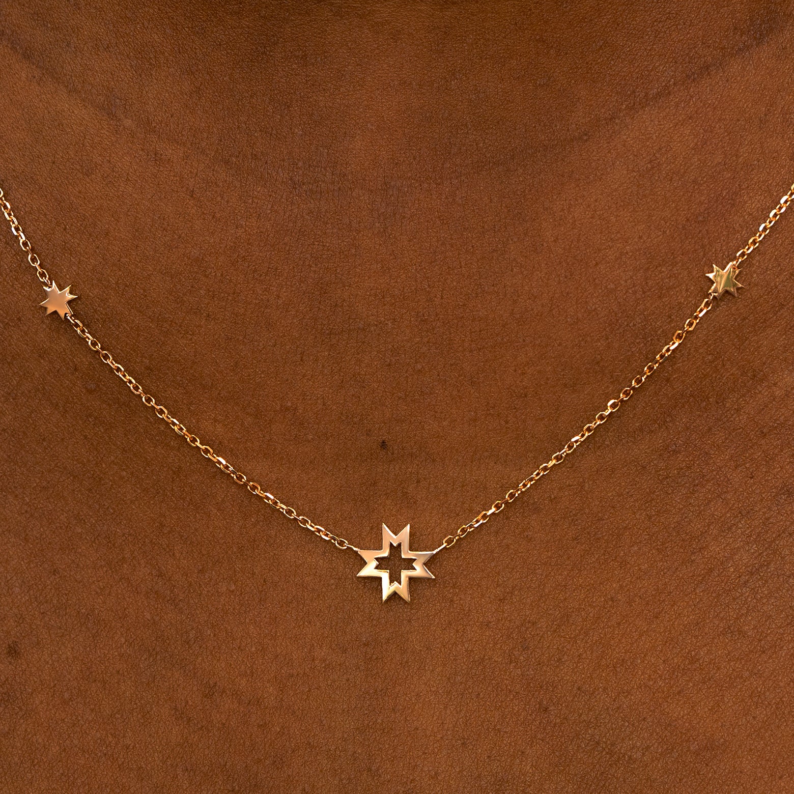 A model wearing a rose gold 8 pointed stars station necklace