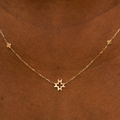 A model wearing a rose gold 8 pointed stars station necklace