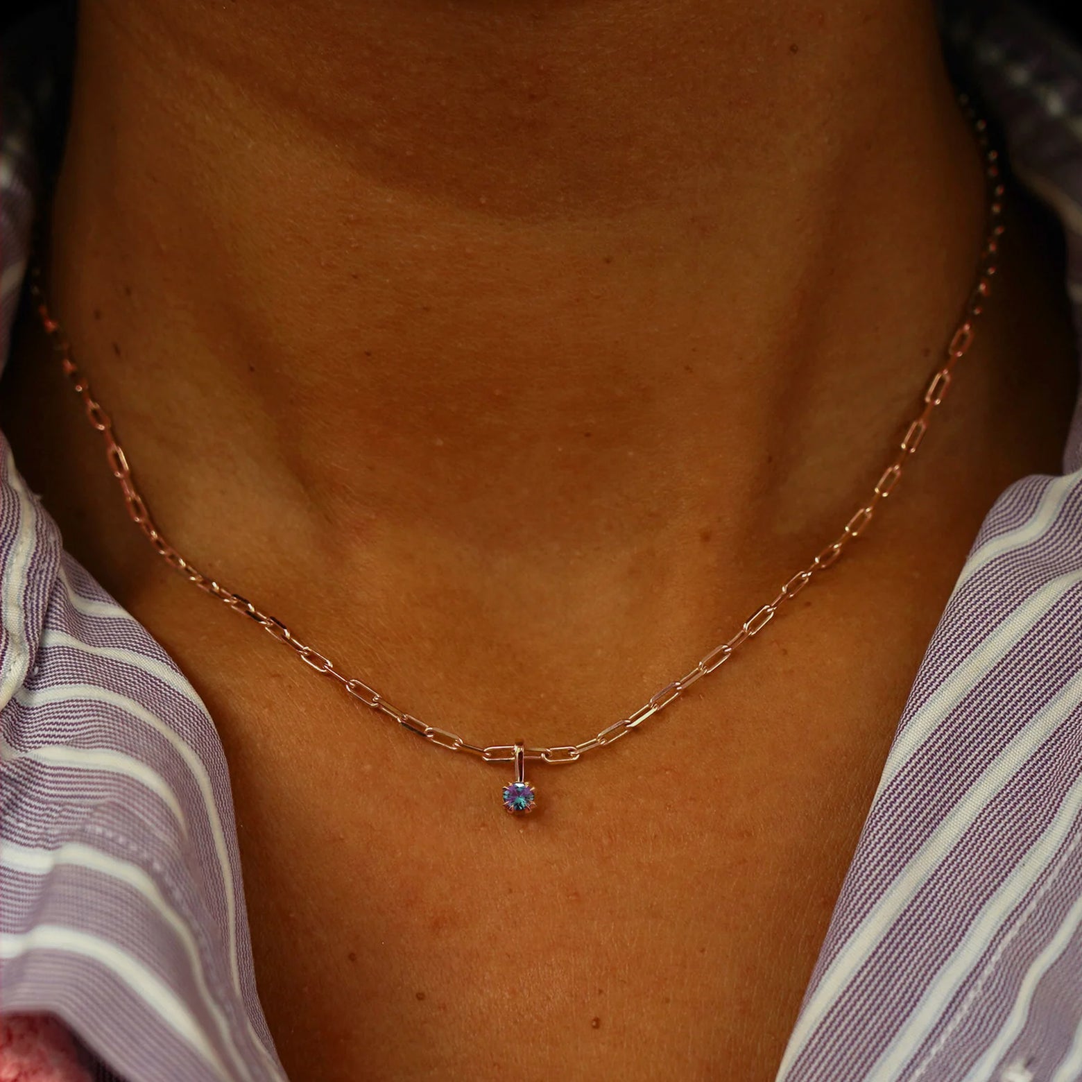 Close up view of a model's neck wearing a rose gold Alexandrite Charm on a Butch Chain