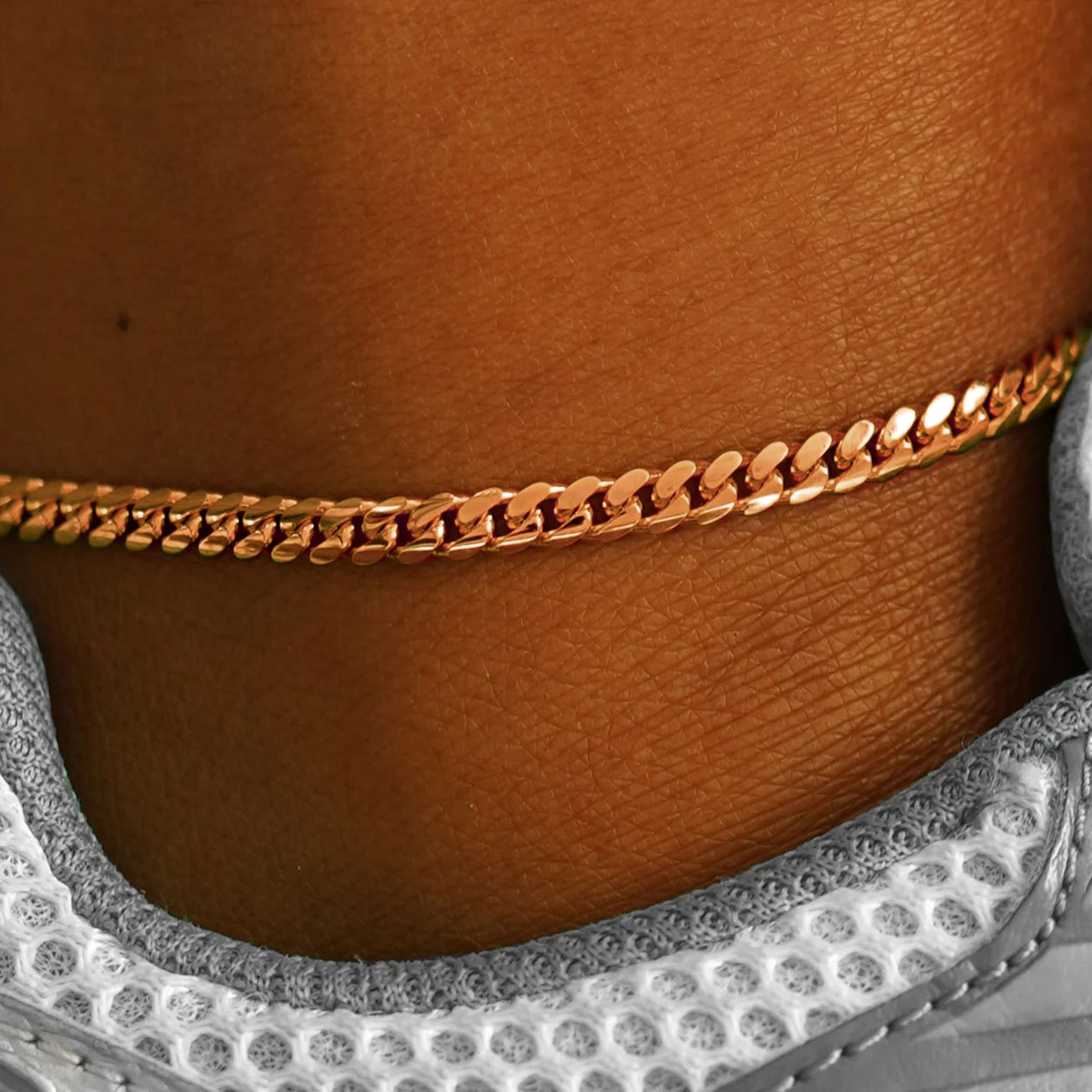 A close up view of model's ankle wear a 14k rose gold Medium Miami Anklet