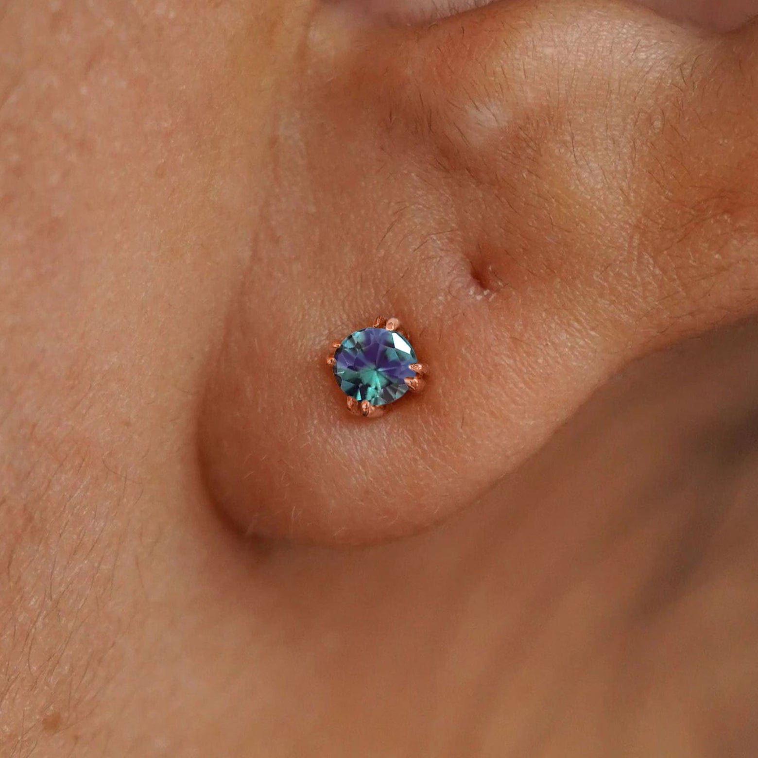 Close up view of a model's ear wearing a 14k rose gold Alexandrite Stud Earring