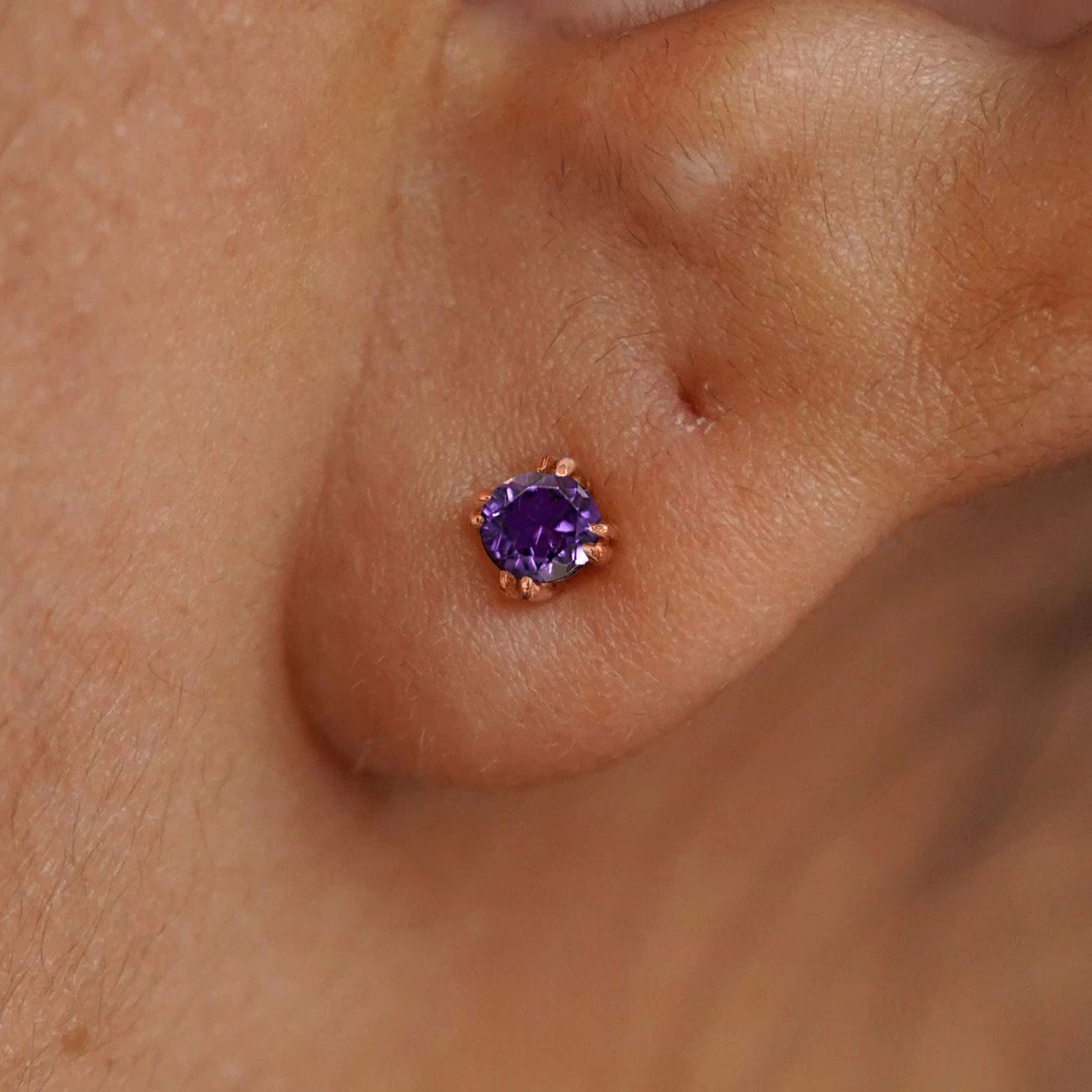 Close up view of a model's ear wearing a 14k rose gold Amethyst Stud Earring