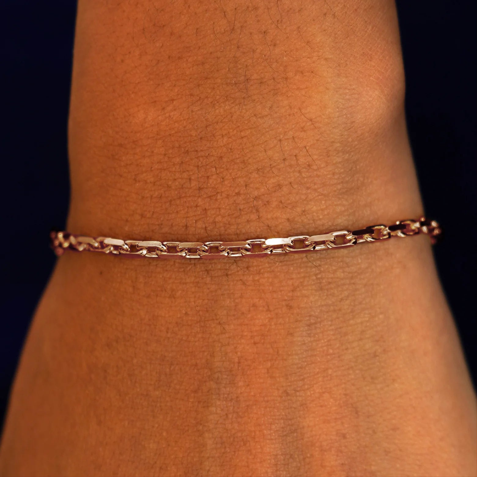 A model's wrist wearing a solid 14k rose gold Anchor Bracelet