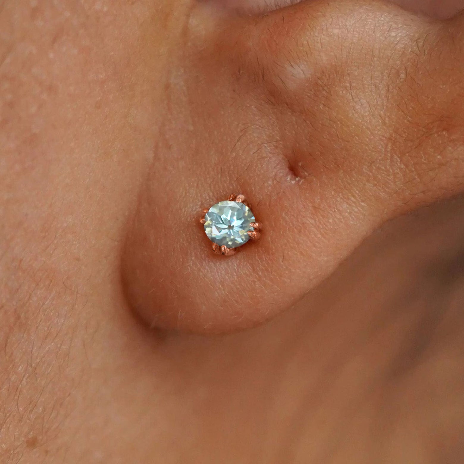Close up view of a model's ear wearing a 14k rose gold Aquamarine Earring