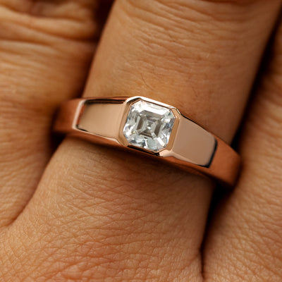 Close up view of a models hand wearing a 14k rose gold asscher lab gemstone ring