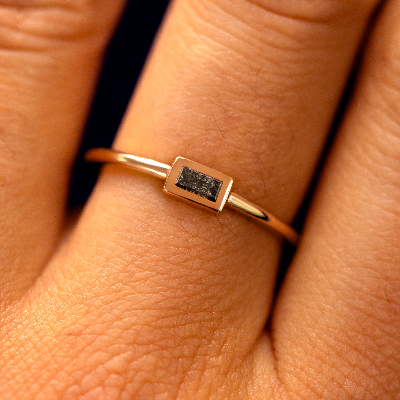 Close up view of a model's fingers wearing a 14k rose gold Baguette Salt and Pepper Diamond Ring
