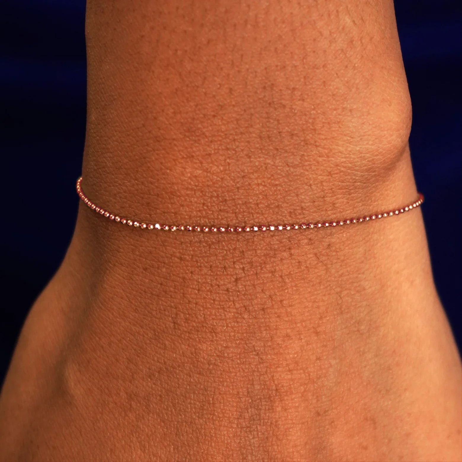 A model's wrist wearing a solid rose gold Bead Bracelet