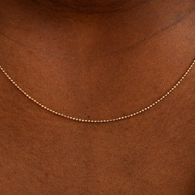 Close up view of a model's neck wearing a solid rose gold Bead Chain