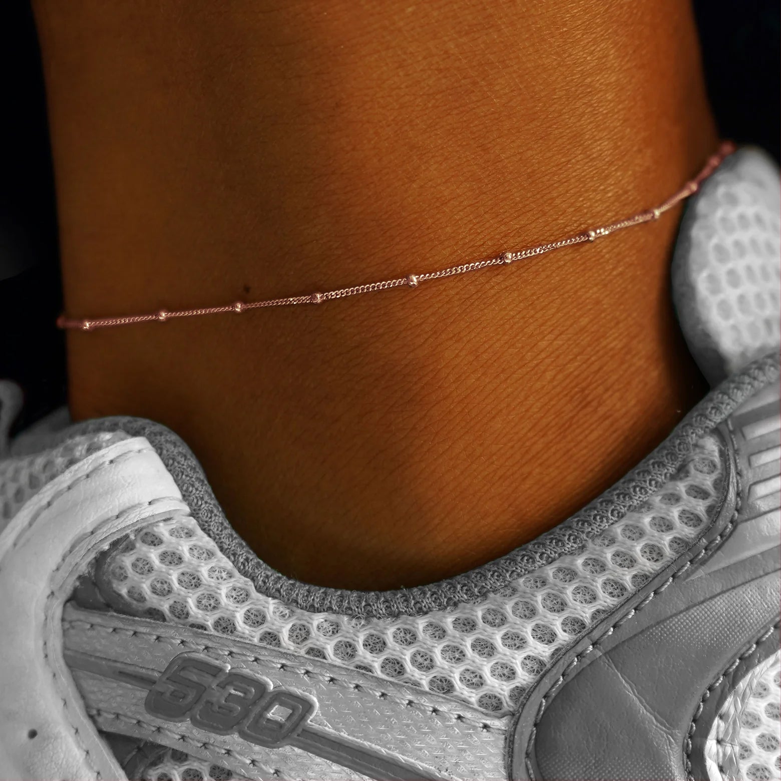 Close up view of a model's ankle wearing a rose gold Beads Anklet