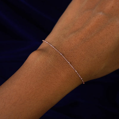 Close up view of a model's wrist wearing a rose gold Beads Bracelet