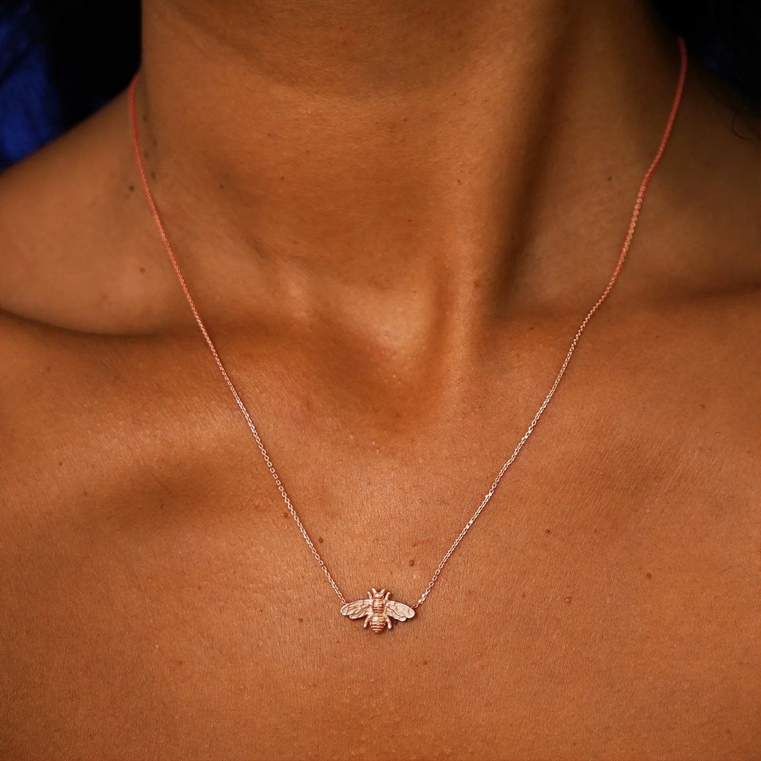 Close up view of a model's neck wearing a solid 14k rose gold Bee Necklace