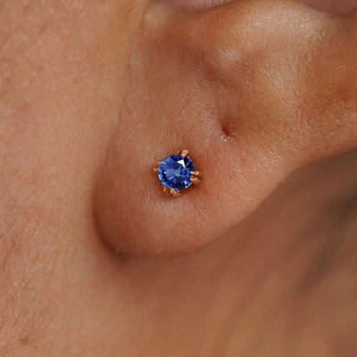 Close up view of a model's ear wearing a 14k rose gold Sapphire Earring