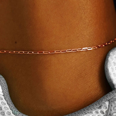 Close up view of a model's ankle wearing a rose gold Butch Anklet