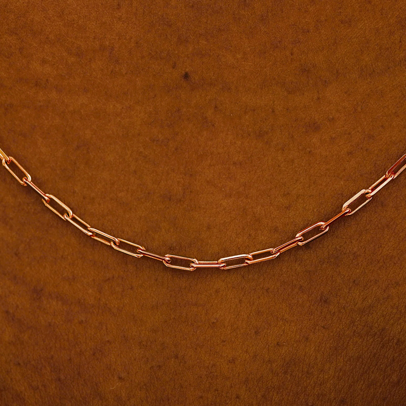 Close up view of a model in a white shirt wearing a solid rose gold Butch Chain