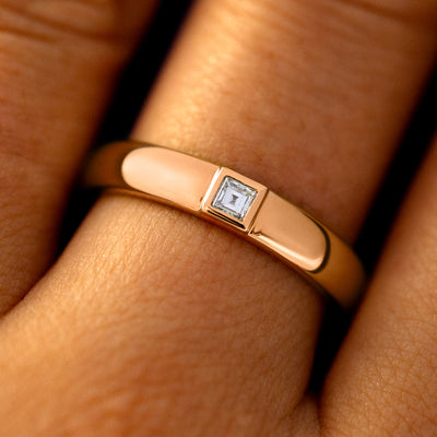 Close up view of a model's fingers wearing a 14k rose gold Square Carre Cut Diamond Band