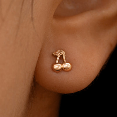 Close up view of a model's ear wearing a 14k rose gold Cherry Earring
