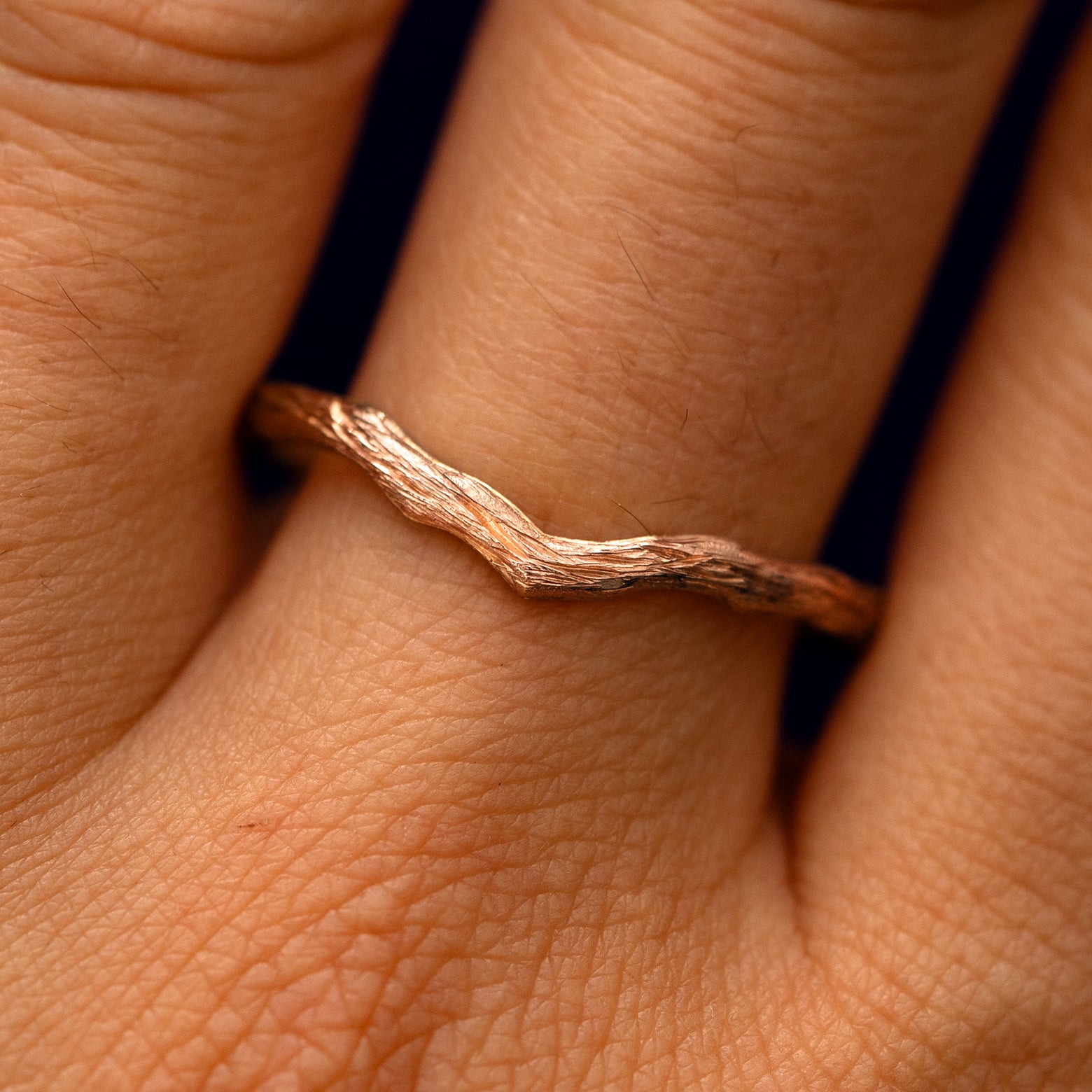 Close up view of a model's fingers wearing a 14k rose gold Chevron Branches Band