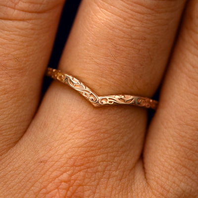 Close up view of a model's fingers wearing a 14k rose gold Chevron Filigree Band