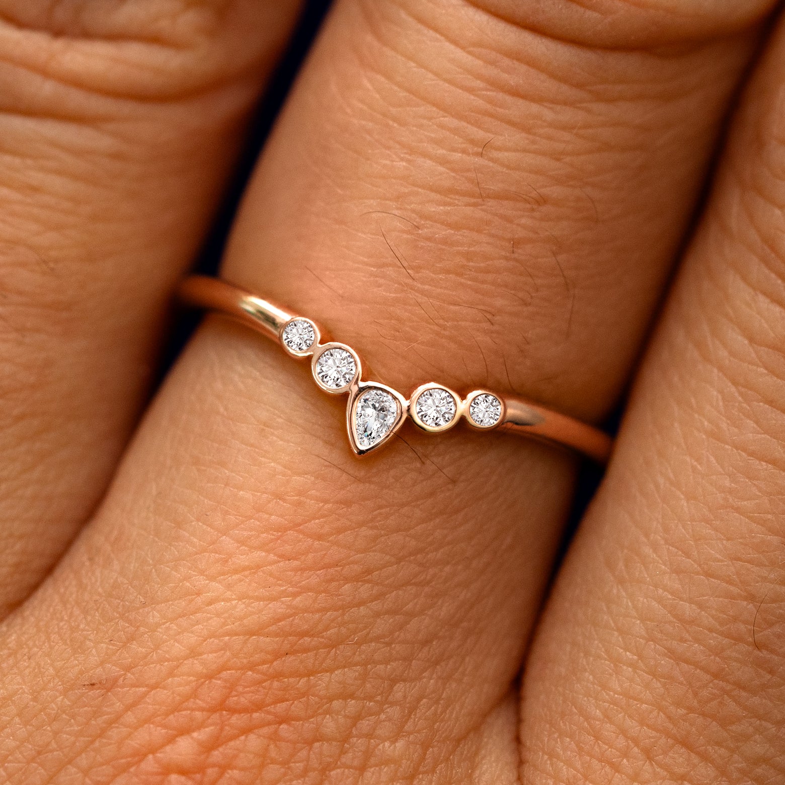 Close up view of a model's fingers wearing a 14k rose gold Chevron Tiara Diamond Band