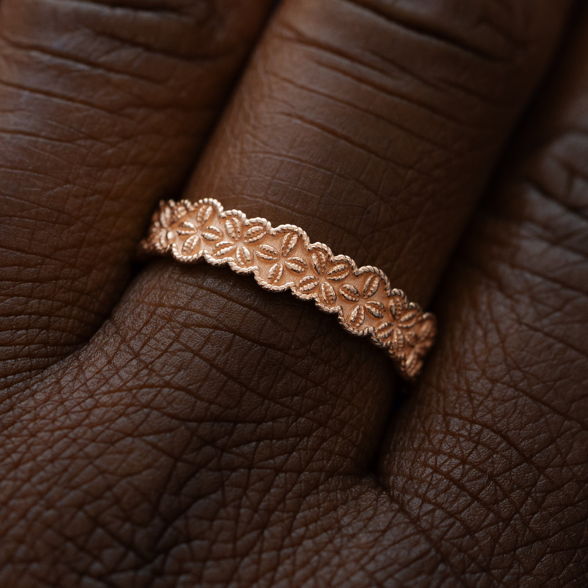 Close up view of a model wearing a solid 14k rose gold cowrie shell flower and rope band