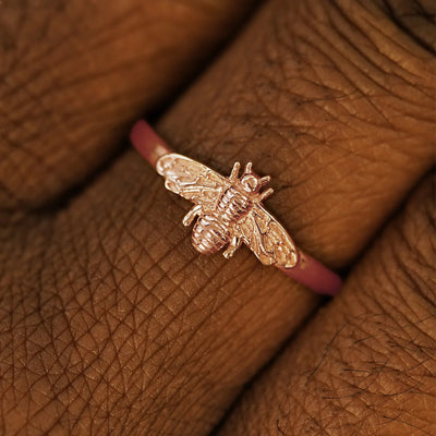 Close up view of a model's hand wearing a 14k solid rose gold Curvy Bee Ring