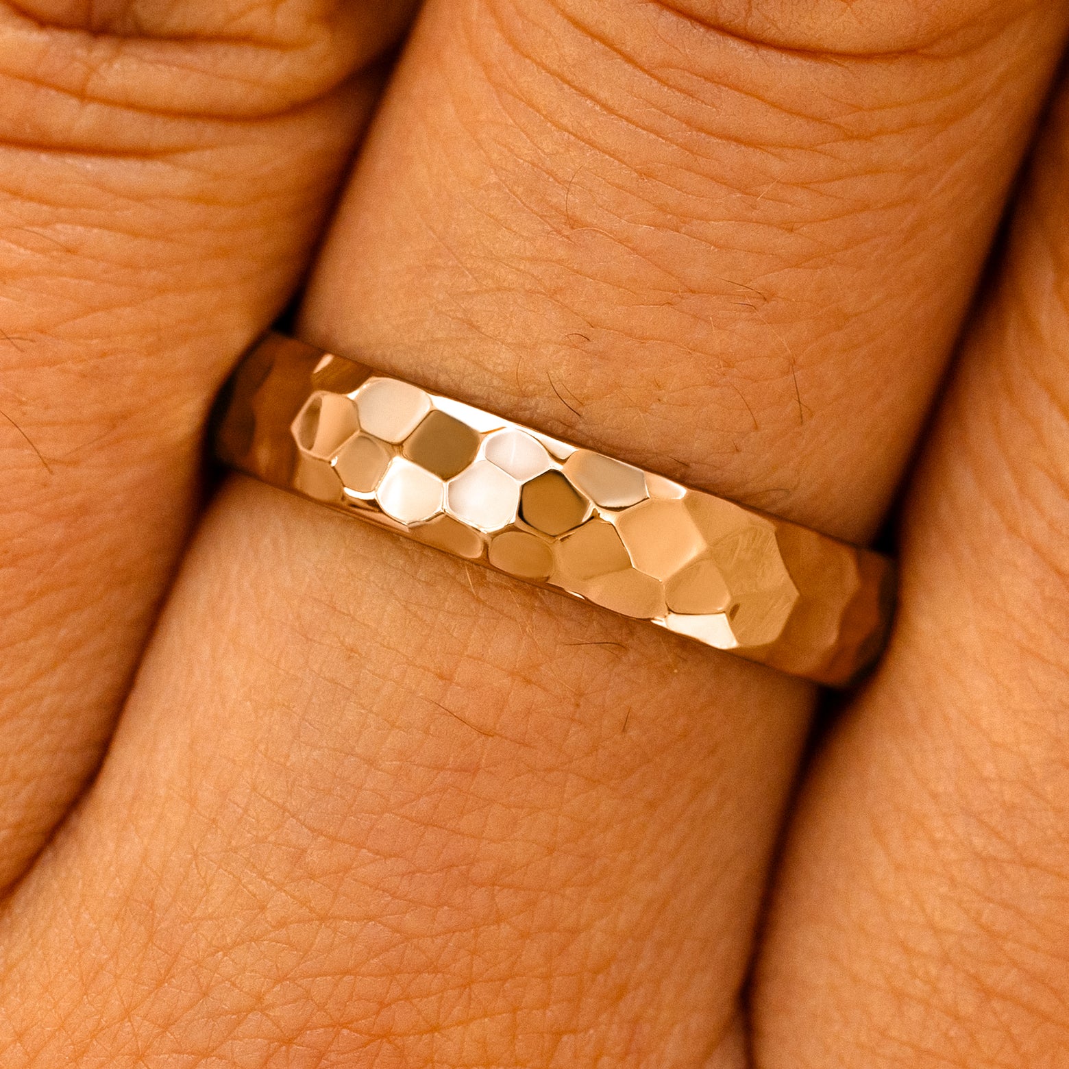 Close up view of a model's fingers wearing a 14k rose gold Curvy Hammered Band