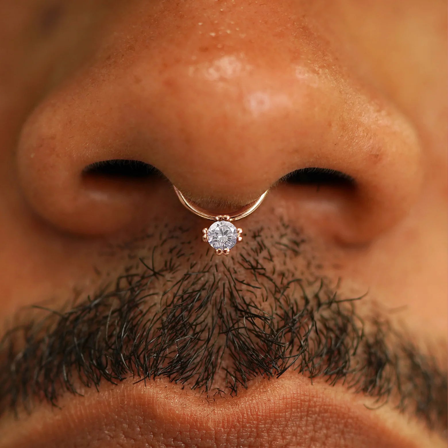 Close up view of a model's face wearing a 14k solid rose gold Diamond Septum