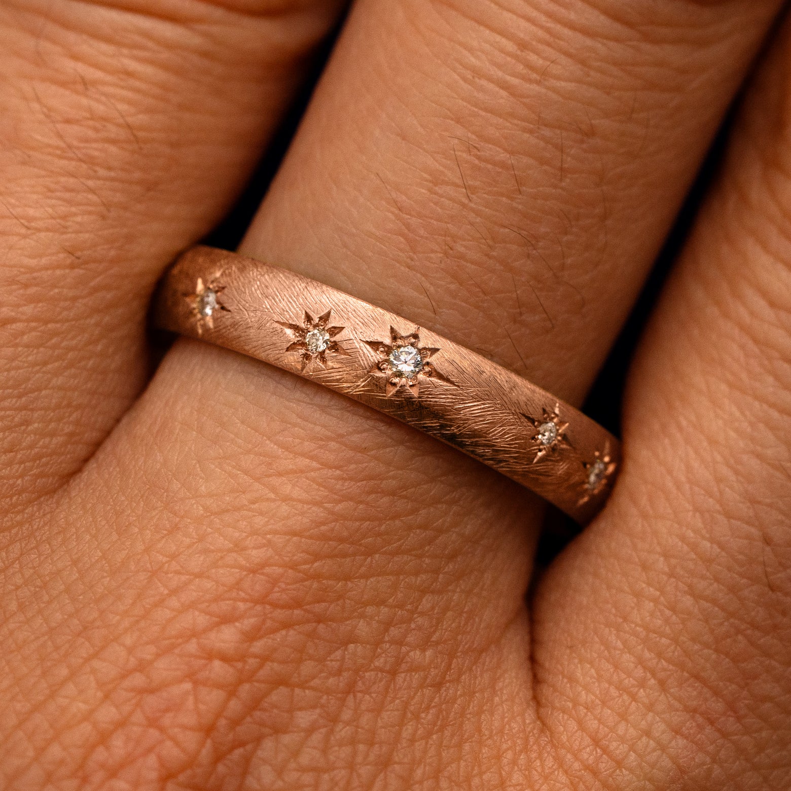 Close up view of a model's fingers wearing a 14k rose gold Curvy Diamond Stars Velvet Band