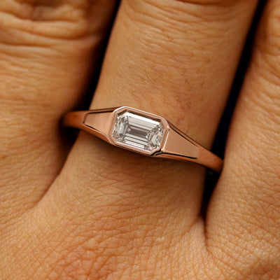 Close up view of a model's fingers wearing a 14k rose gold Emerald Cut Lab Created Diamond Signet Ring
