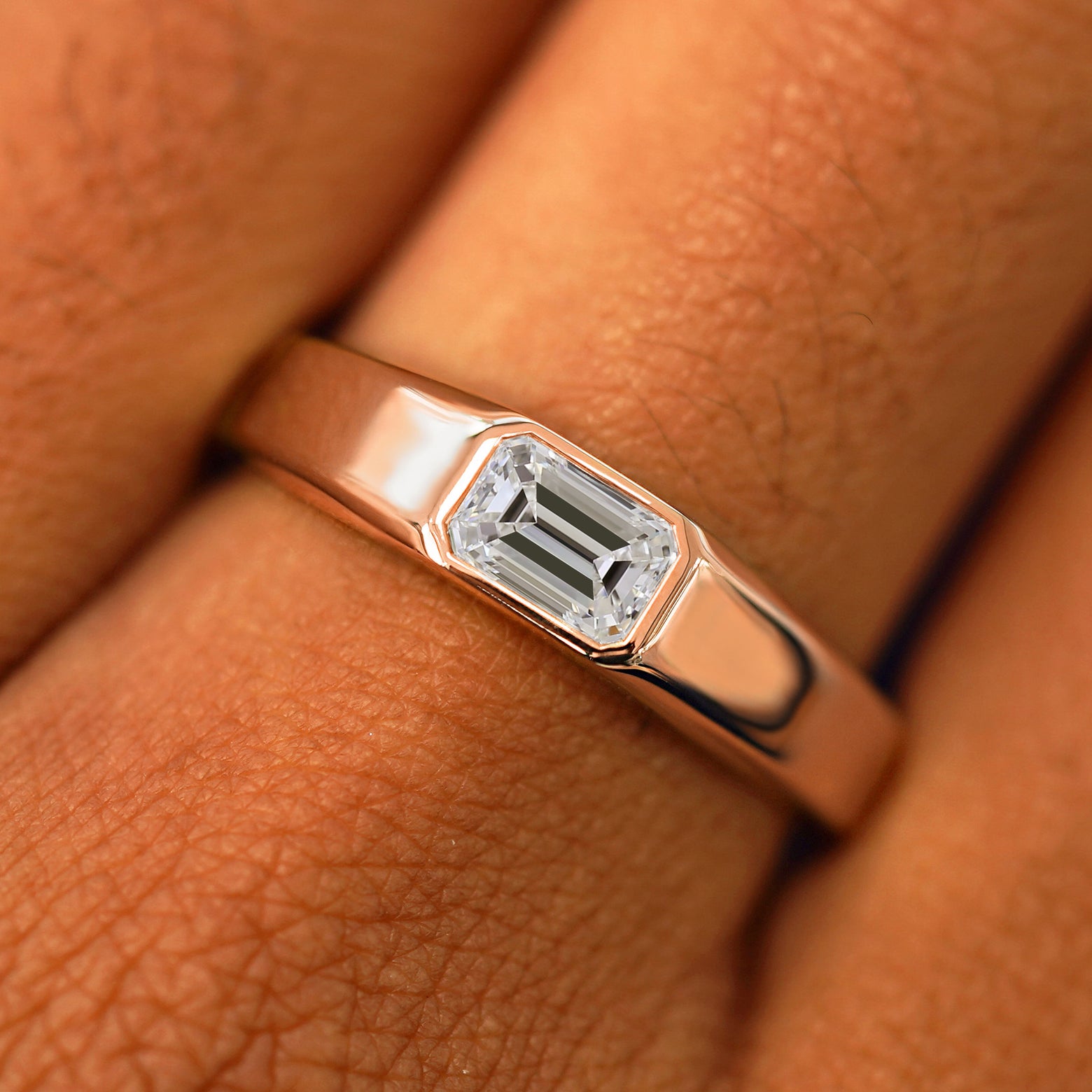 Close up view of a model's fingers wearing a 14k rose gold Emerald Cut Lab Created Diamond Signet Ring