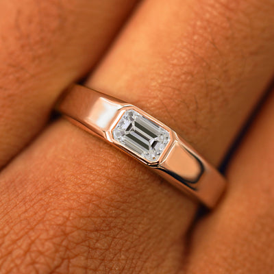 Close up view of a model's fingers wearing a 14k rose gold Emerald Cut Lab Created Diamond Signet Ring