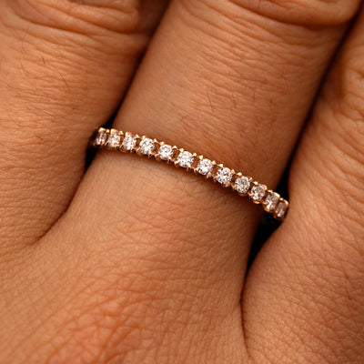 Close up view of a model's fingers wearing a 14k rose gold Mini Petal Set Diamond Eternity Band
