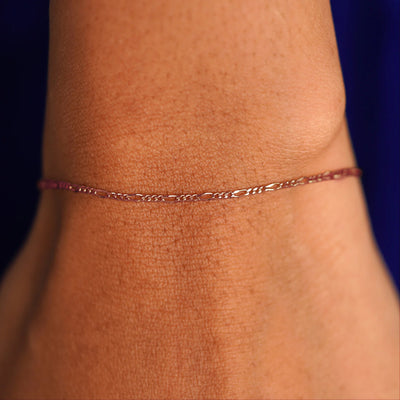 Close up view of a model's wrist wearing a solid rose gold Figaro Bracelet