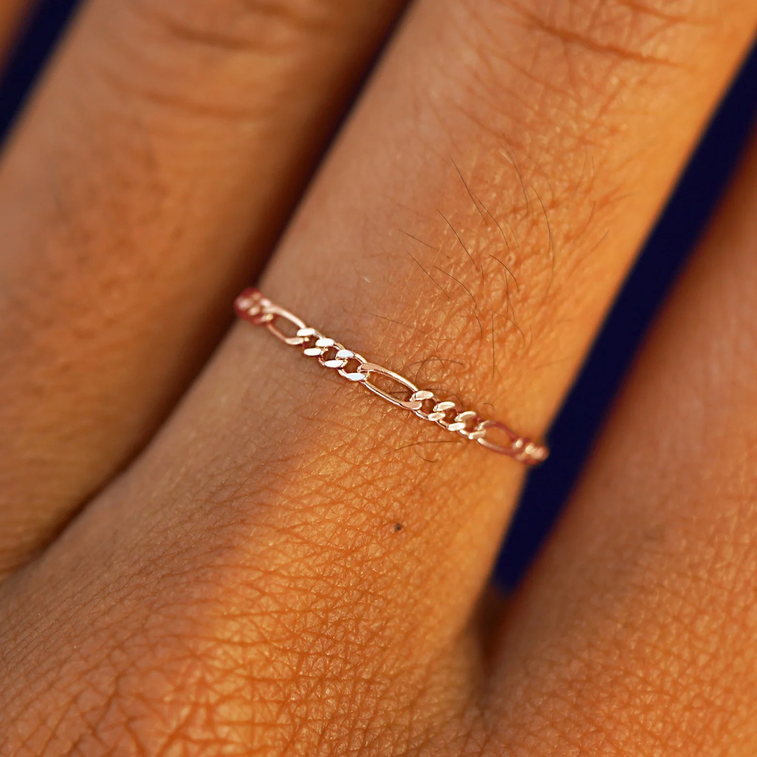 Close up view of a model's hand wearing a solid rose gold Figaro Ring