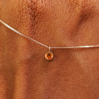 Close up view of a 14k rose gold Fire Opal Necklace draped across the back of a model's hand
