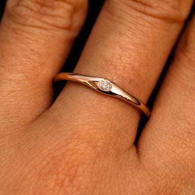 A 14k rose gold Flush Set Oval Diamond Ring on a model's finger