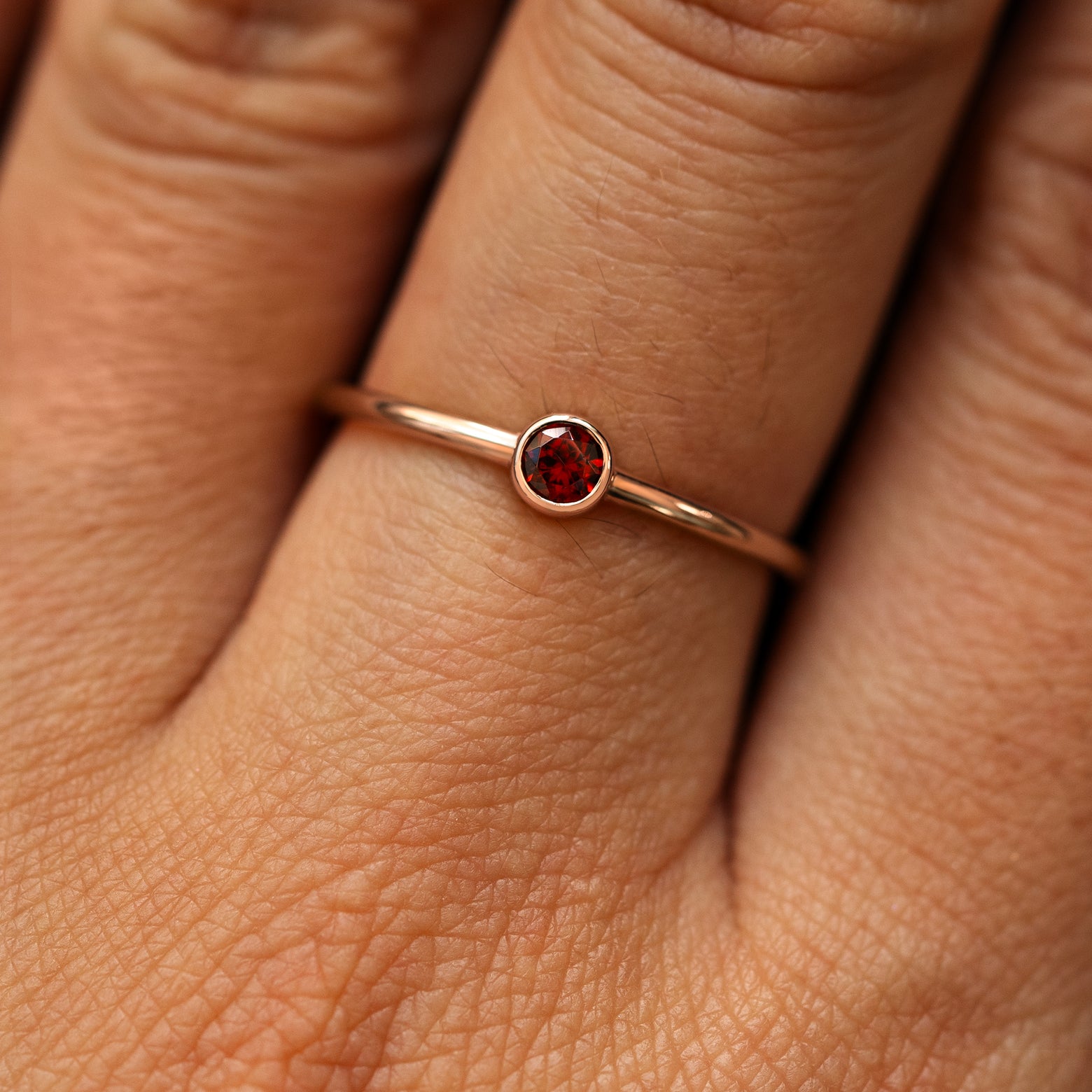 Close up view of a model's fingers wearing a 14k rose gold Garnet Ring